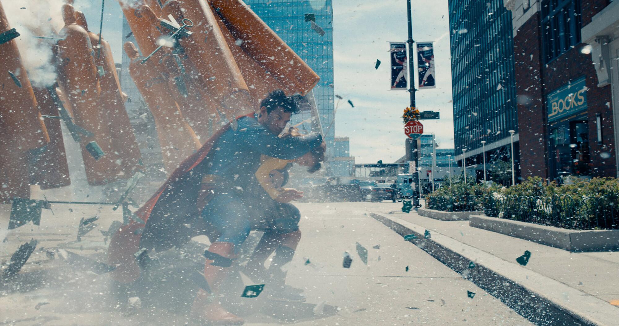 A superhero shields a bystander from debris.