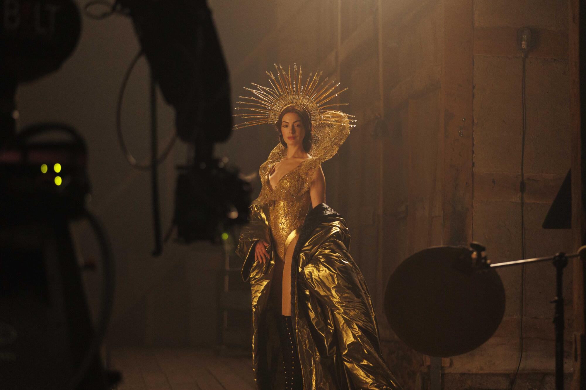 A woman poses in a gold dress and headpiece.