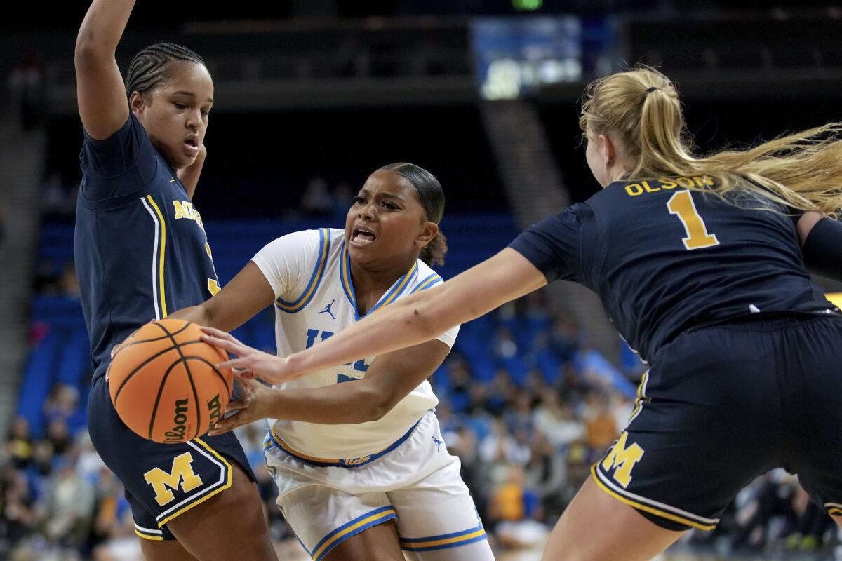 UCLA guard Londynn Jones, center, drives to the basket against Michigan guards Mila Holloway, left, and Olivia Olson.