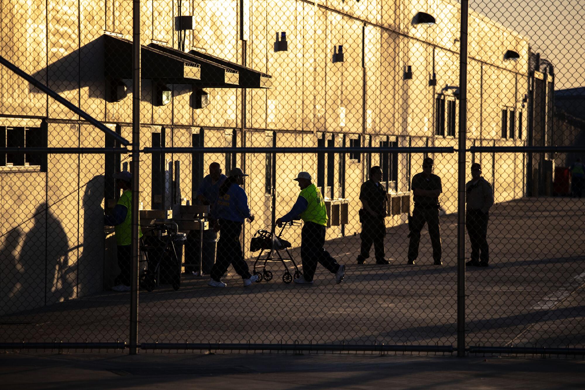 People seen behind a wire fence, outside a building