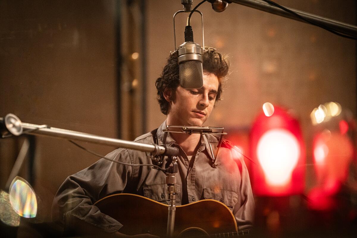 A man plays a guitar in a recording studio.