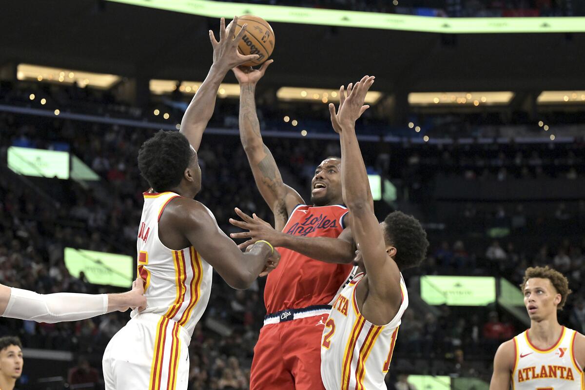 Clippers forward Kawhi Leonard, center, tries to shoot over Atlanta's Clint Capela, left, and De'Andre Hunter.