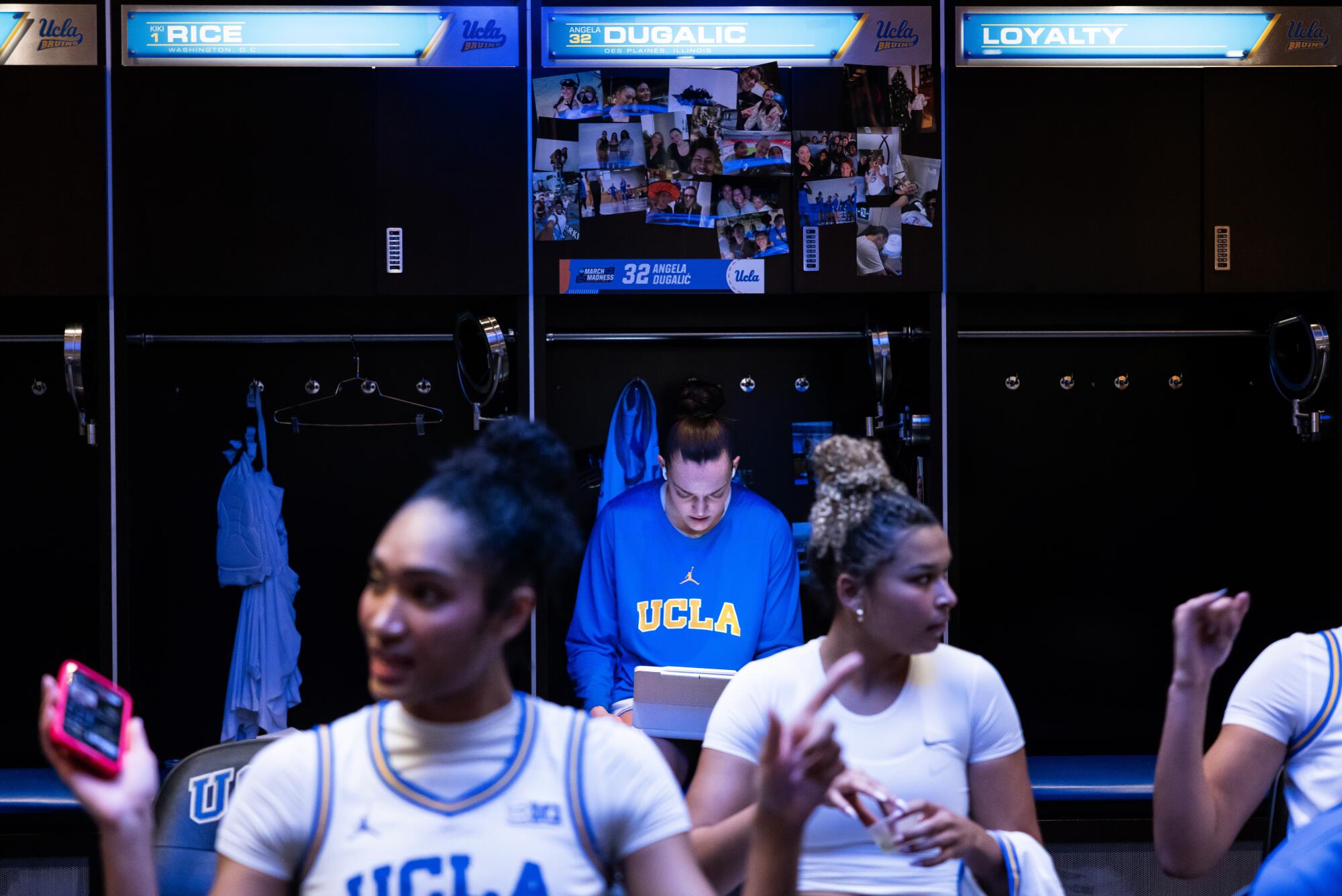 UCLA's Angela Dugalic, center, sits at her locker in the women's basketball locker room.