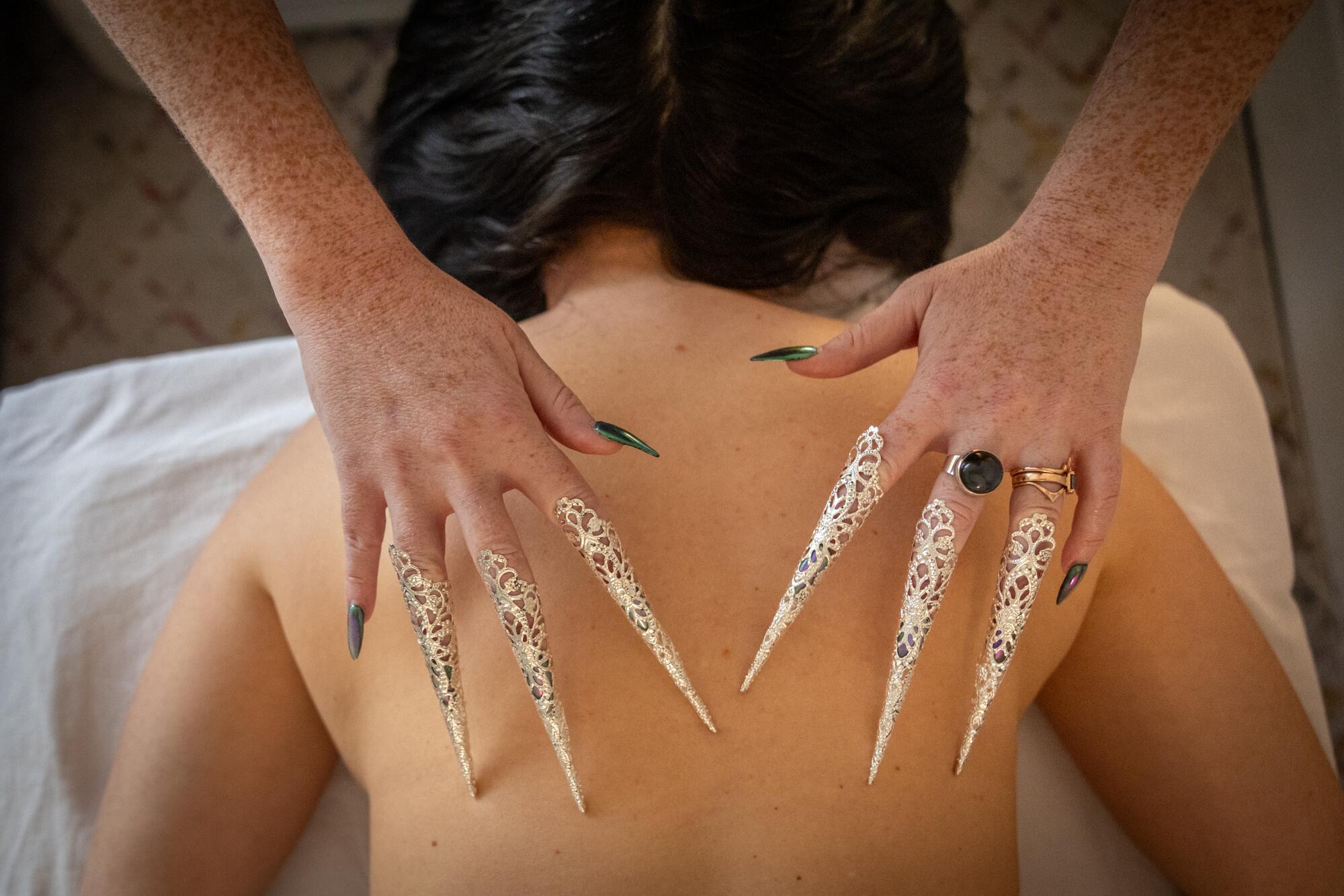 A woman scratching another woman's back with long nails.