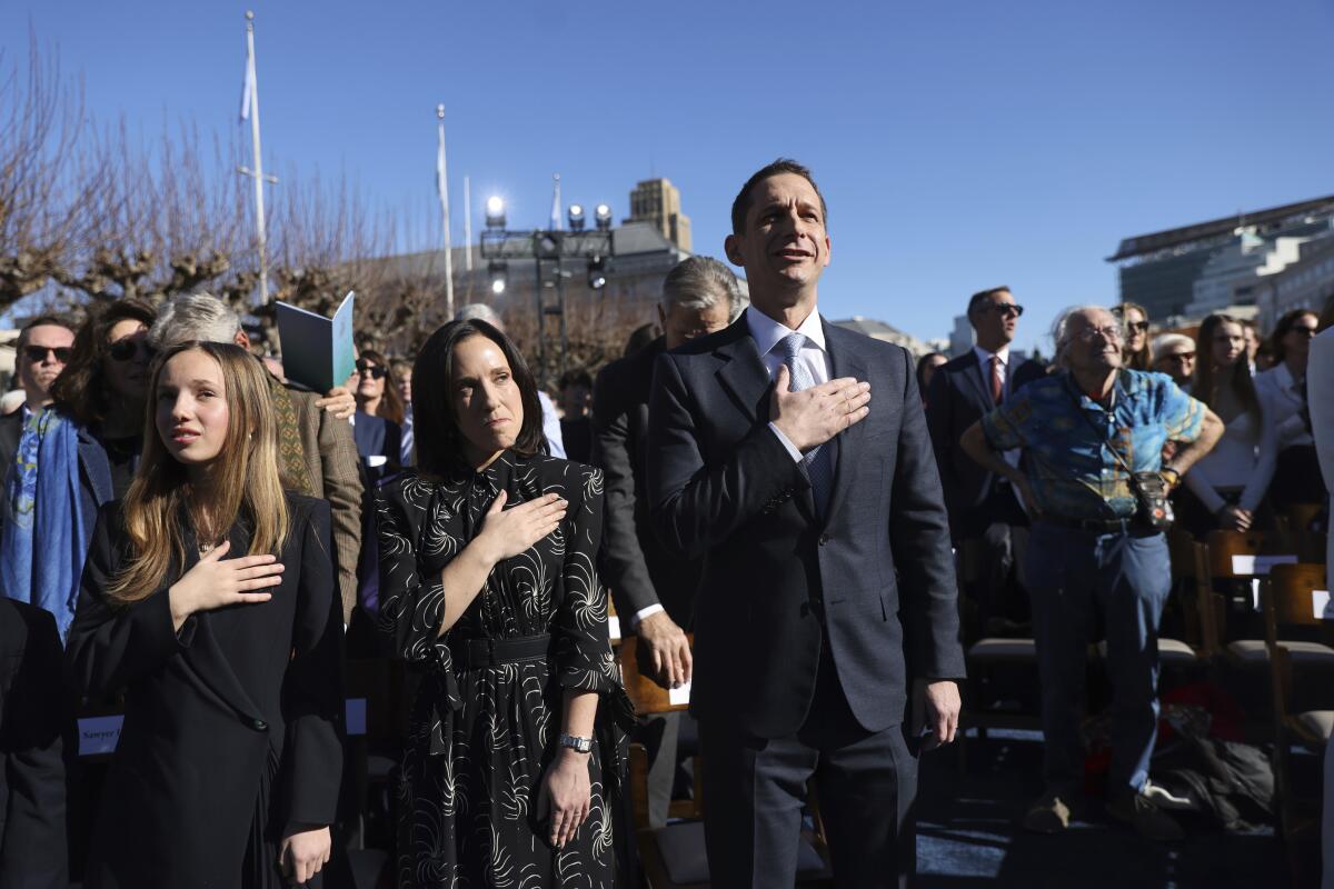 Mayor-elect Daniel Lurie and his wife, Becca Prowda, put hands to their hearts during an outdoor ceremony.