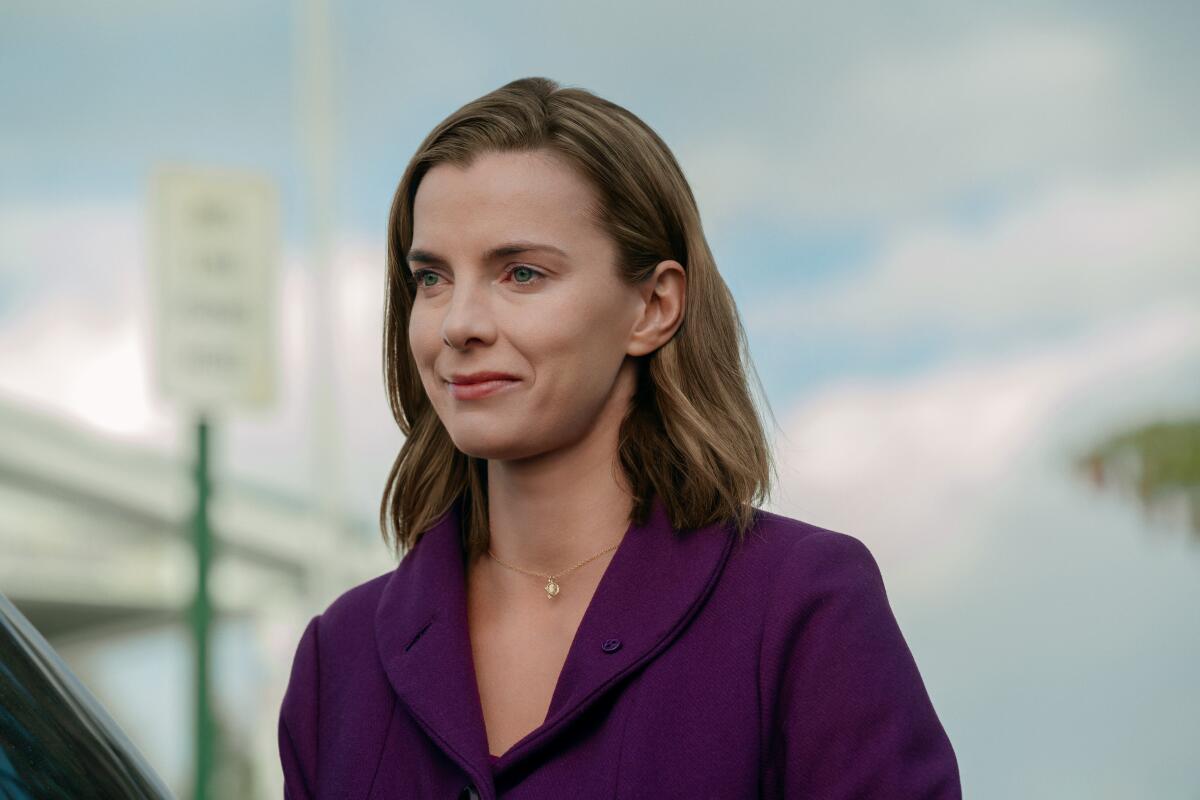 A woman in purple jacket smiling.