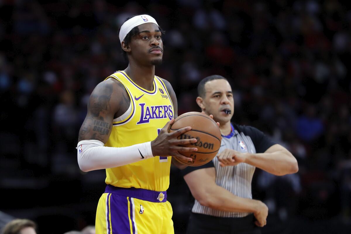 Lakers forward Jarred Vanderbilt, left, throws in the ball next to referee Curtis Blair.