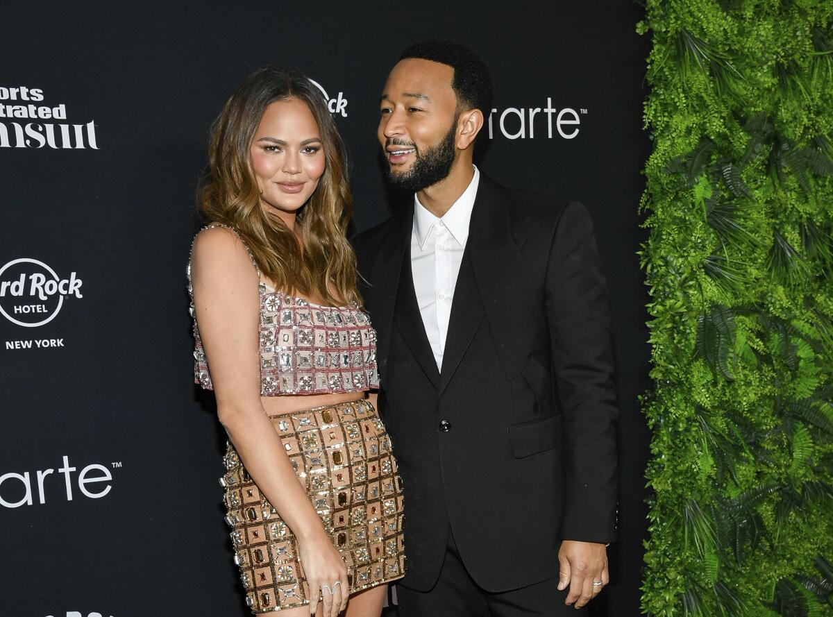 Chrissy Teigen and John Legend left smile and pose in cocktail attire