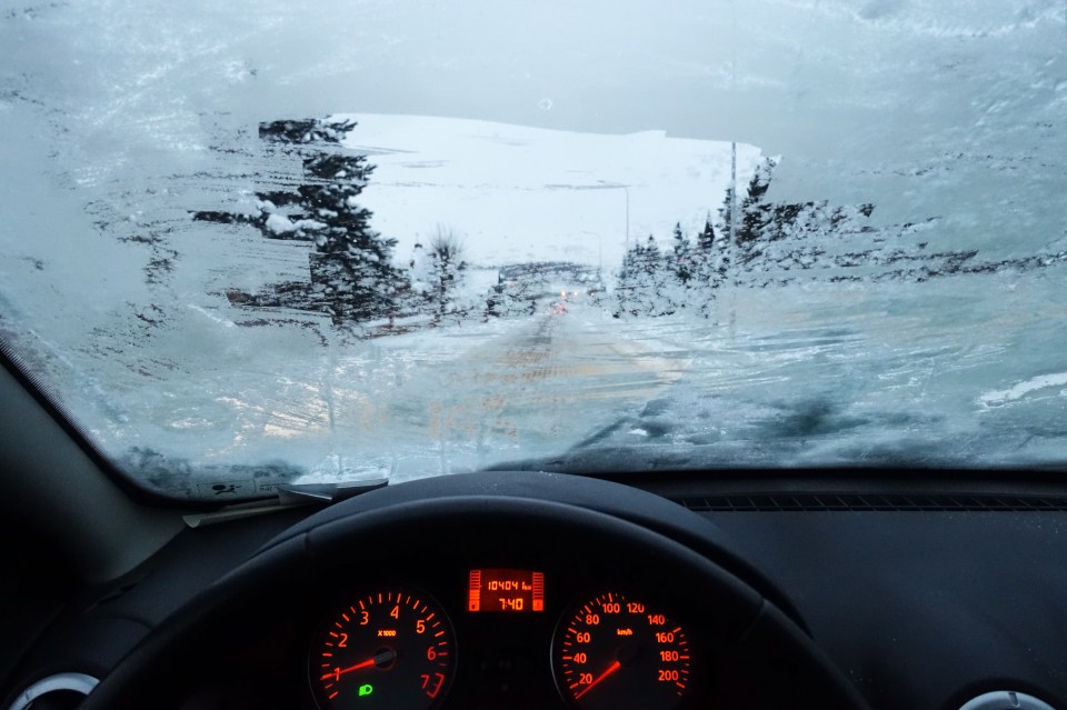 Driver's view of a snow-covered road from inside a Dacia Sandero.