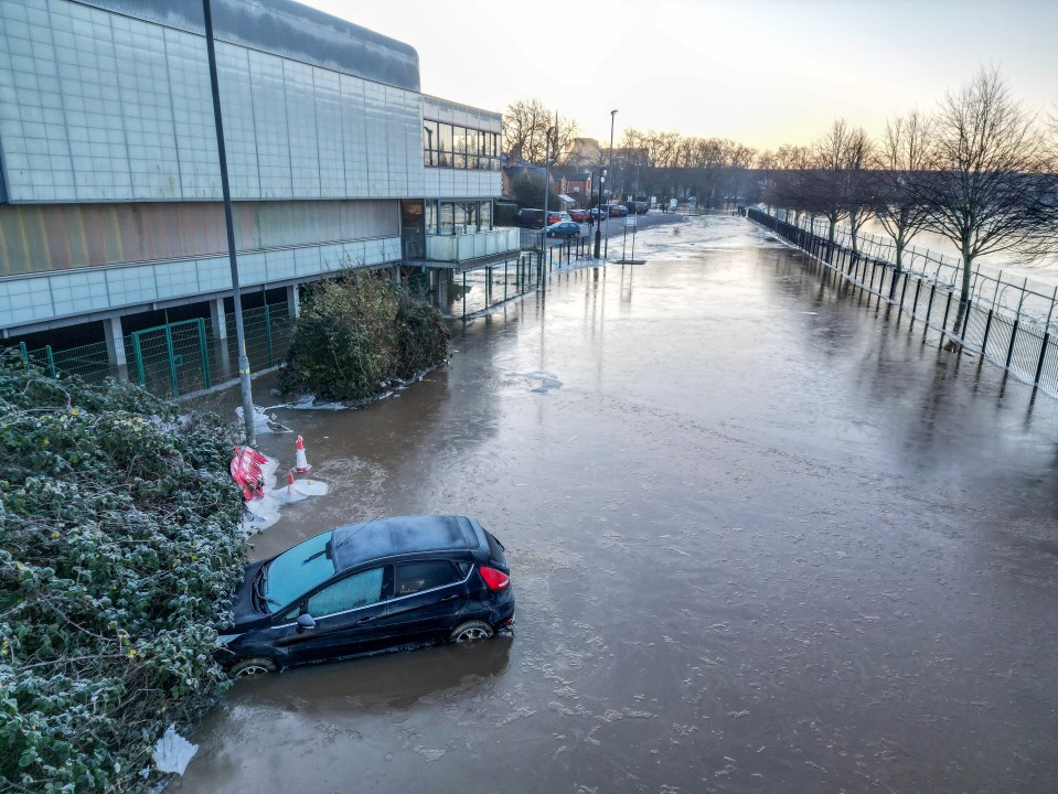 Car submerged in icy floodwater.