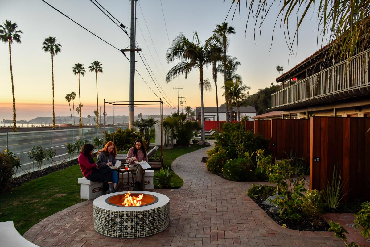 Three guests from Los Angeles sit by a fire pit at El Caminante Bar & Bungalows at Capistrano Beach in Dana Point.