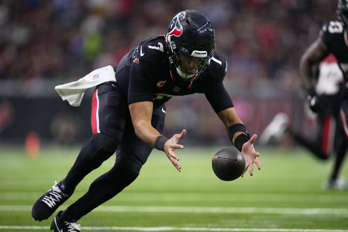 The Texans' C.J. Stroud readies to grab a bad shotgun snap and then scrambles before completing a 34-yard pass. 