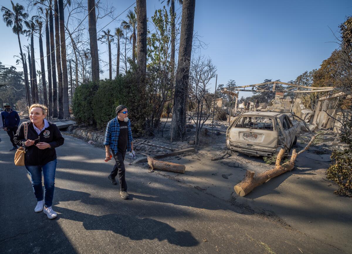 Kathryn Barger and Pierre Dupuy walk on a fire-damaged street