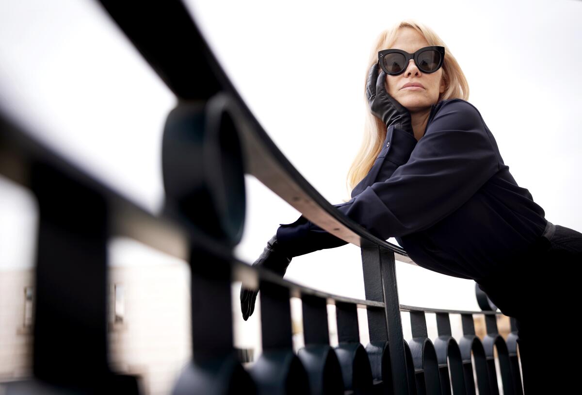 Wearing dark sunglasses, Pamela Anderson leans on an outdoor railing in "The Last Showgirl."