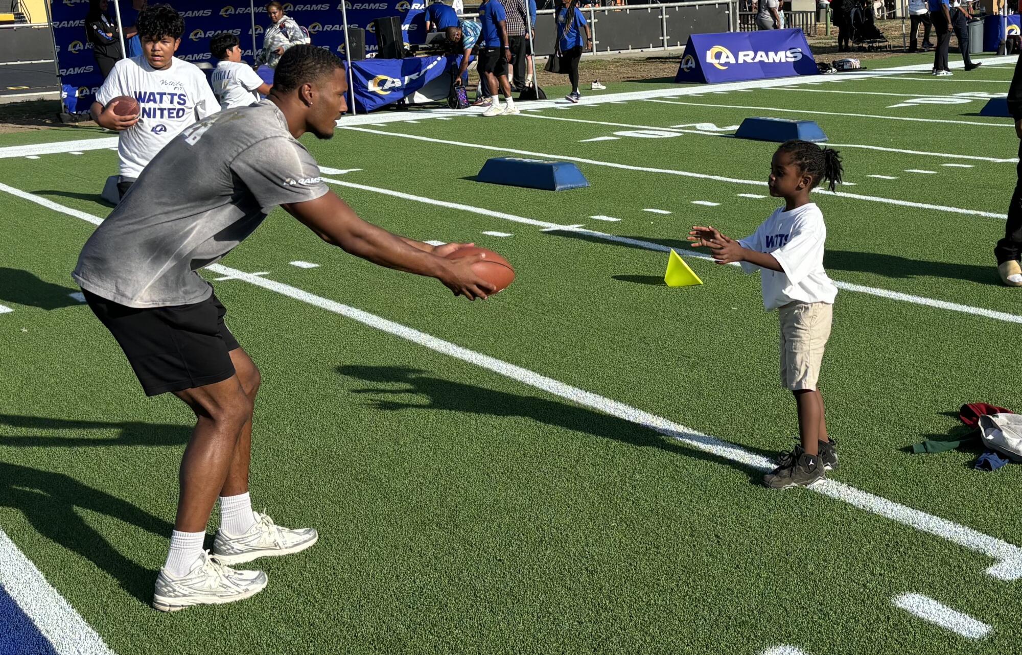 Rams safety Quentin Lake instructs a youngster during the dedication of the Rams football field in Watts.