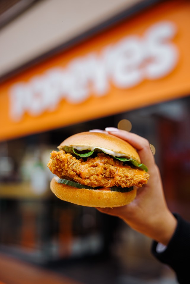 A hand holding a Popeyes chicken sandwich.