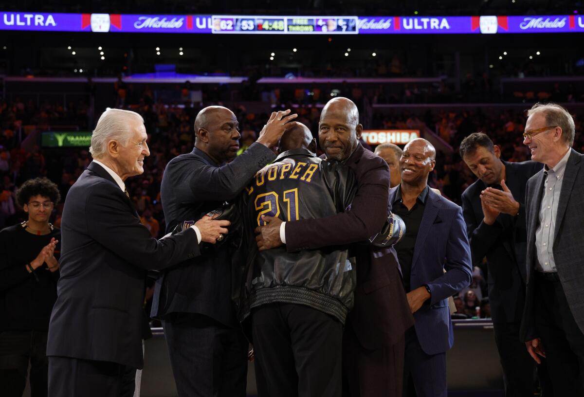 Michael Cooper, center, is mobbed by former teammates.