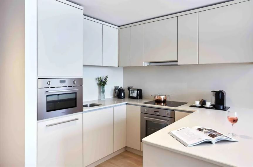 Modern kitchen with white cabinets and stainless steel appliances.