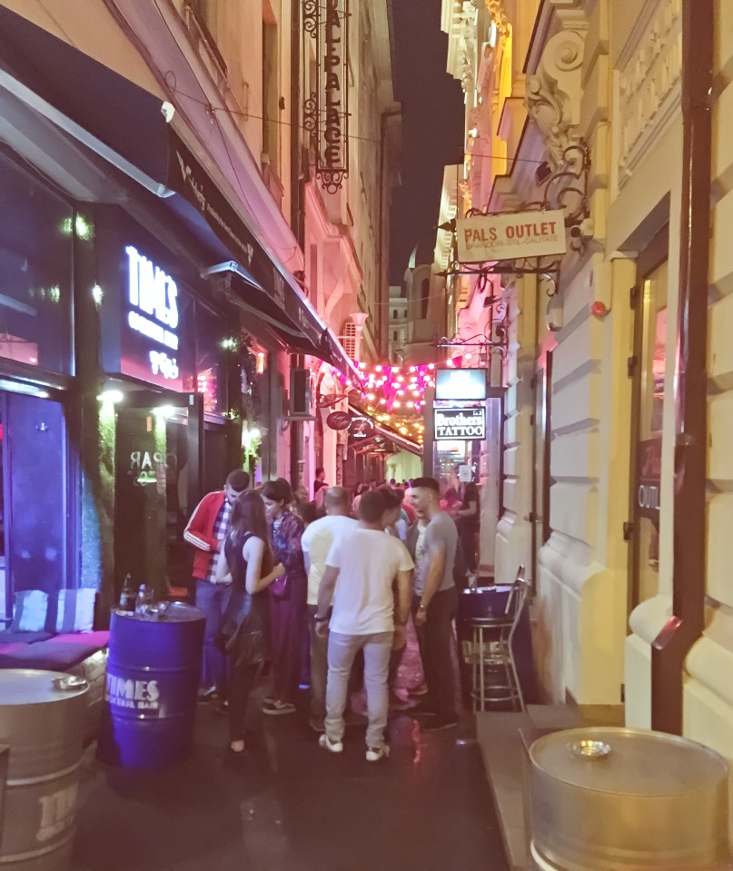 Crowd of people at night in a narrow alleyway with pubs and bars in Bucharest, Romania.