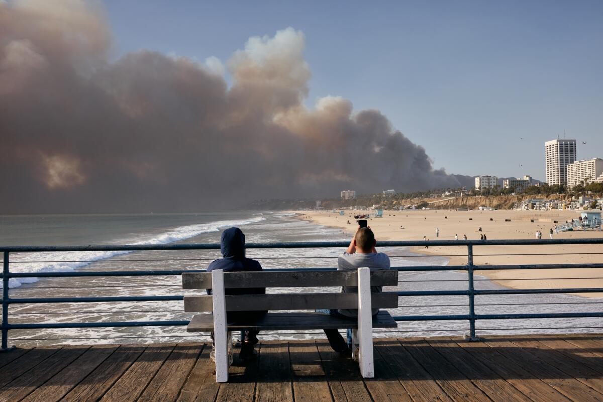 The Palisades fire burns in the distance, as seen from the Santa Monica Pier on Jan. 7.