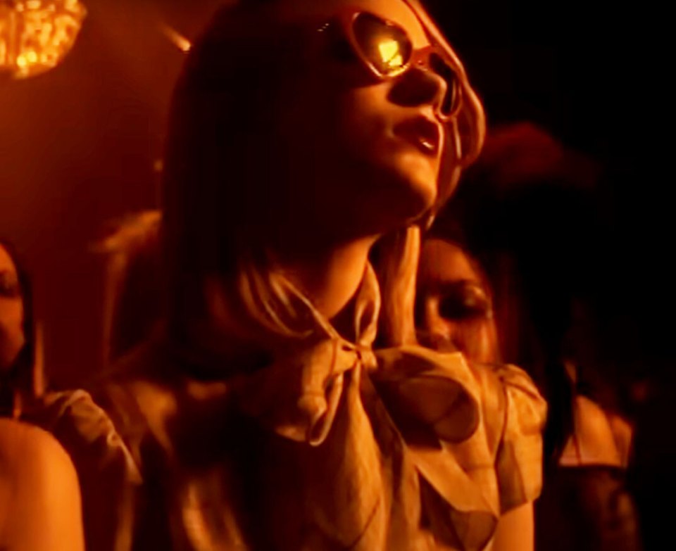 Woman wearing heart-shaped sunglasses in dimly lit room.