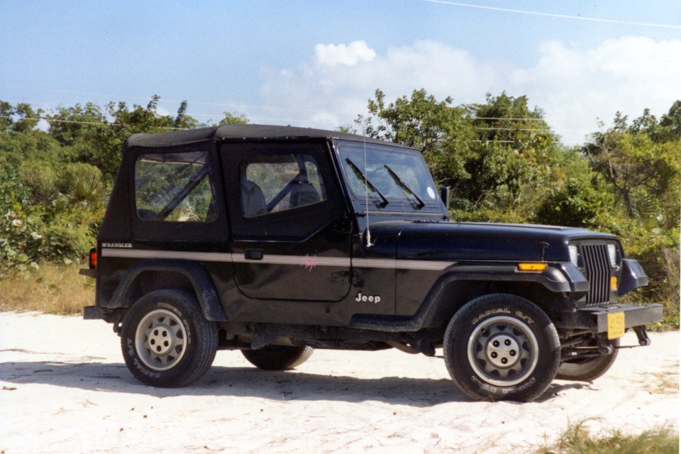 Black Jeep Wrangler on a sandy beach.