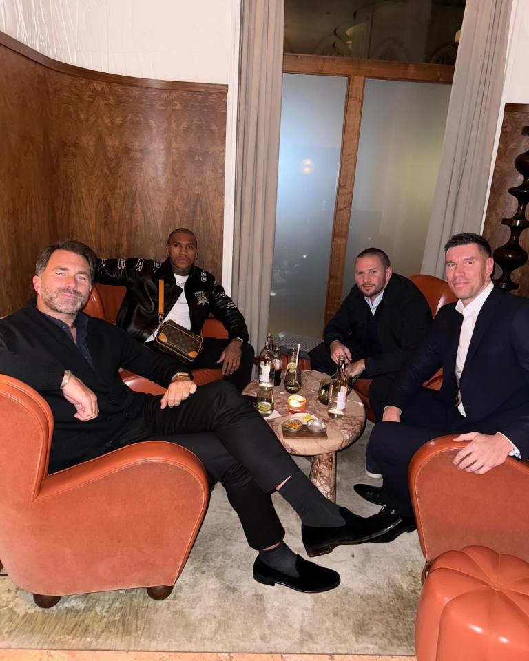 Four men sitting in armchairs at a bar.