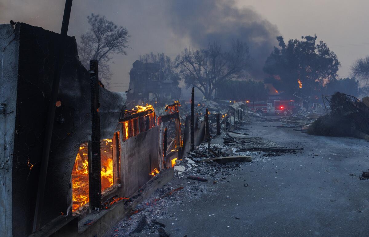 Gutted homes continue to burn slowly, embers glowing orange. 