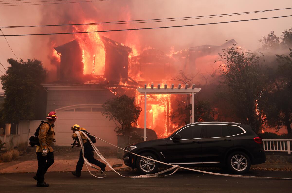 Firefighters battle a house fire off Bollinger Drive in Pacific Palisades