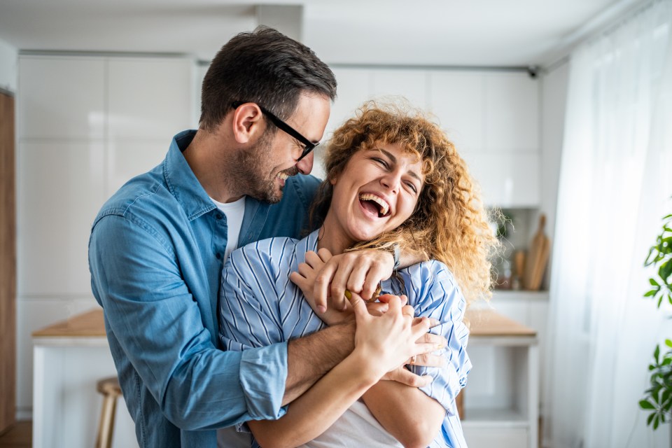 A happy couple embracing in their kitchen.