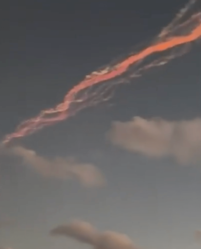 Pink and orange contrail in the sky.