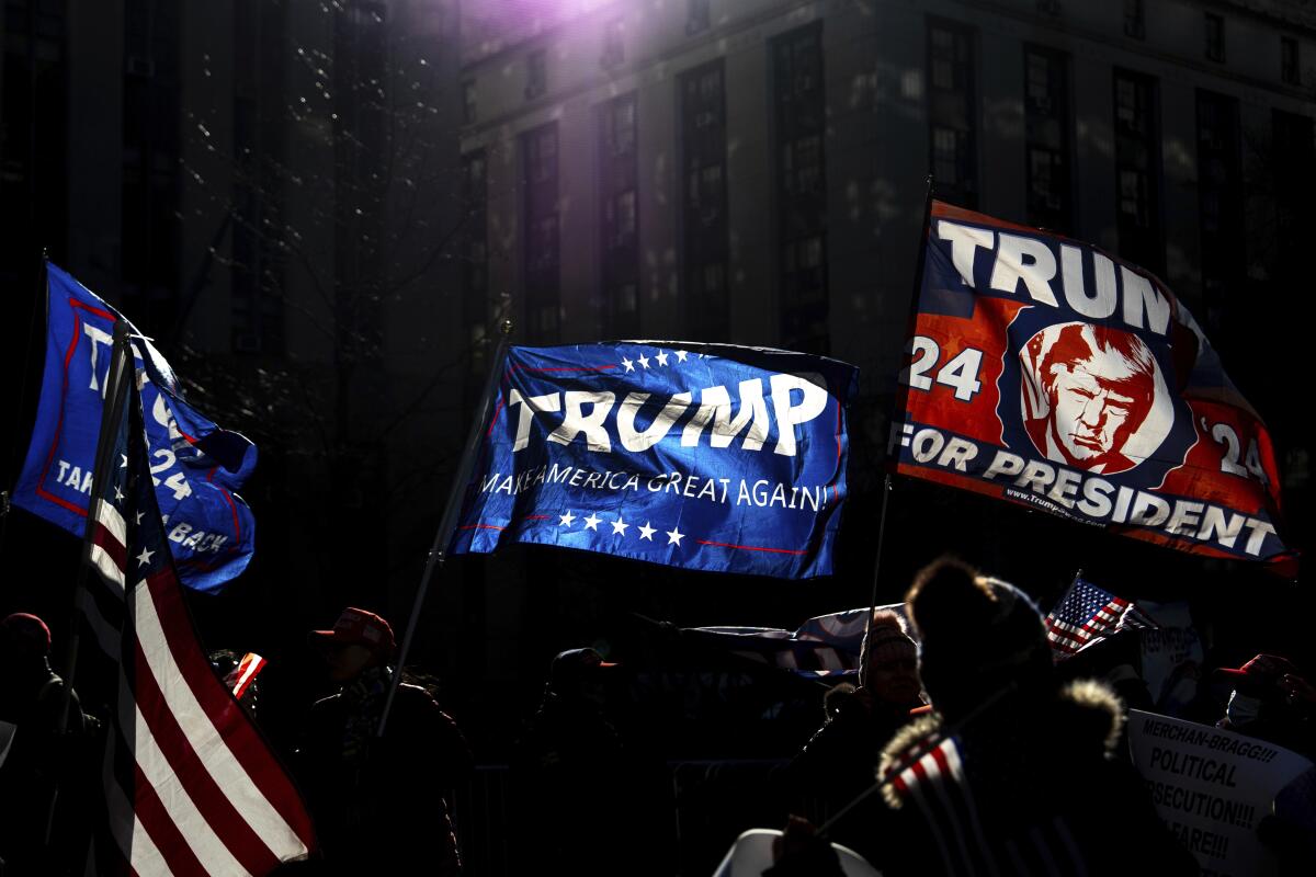 Flags in blue and red, one with a man's image and the word Trump