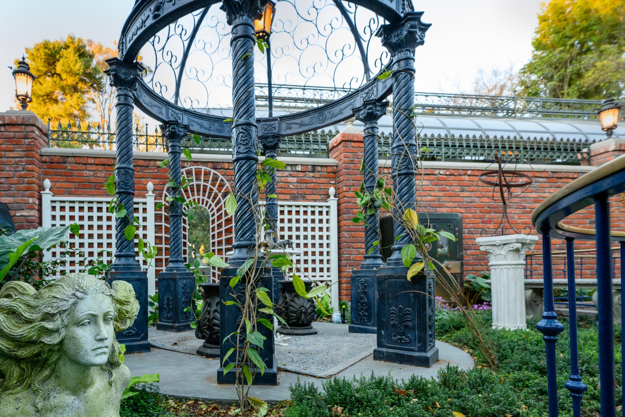 A garden with a gazebo and forlorn statues. 