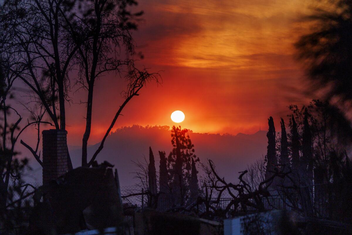 A smoky haze fills the dusk landscape as a home smolders in the foreground during the Eaton fire in Altadena, California.