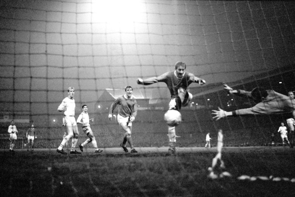 GBJY7C Manchester United's Denis Law (second r) fires his team's third goal past Arsenal goalkeeper Jim Furnell (r, diving), watched by teammate David Herd (c) and Arsenal's Ian Ure (l) and Frank McLintock (second l)