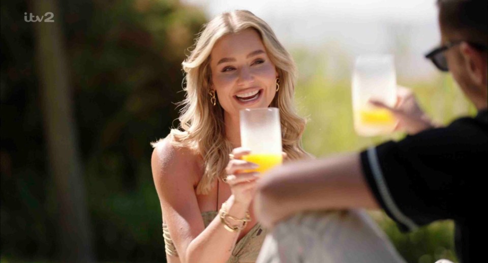 A woman and a man on a date, toasting with orange juice.