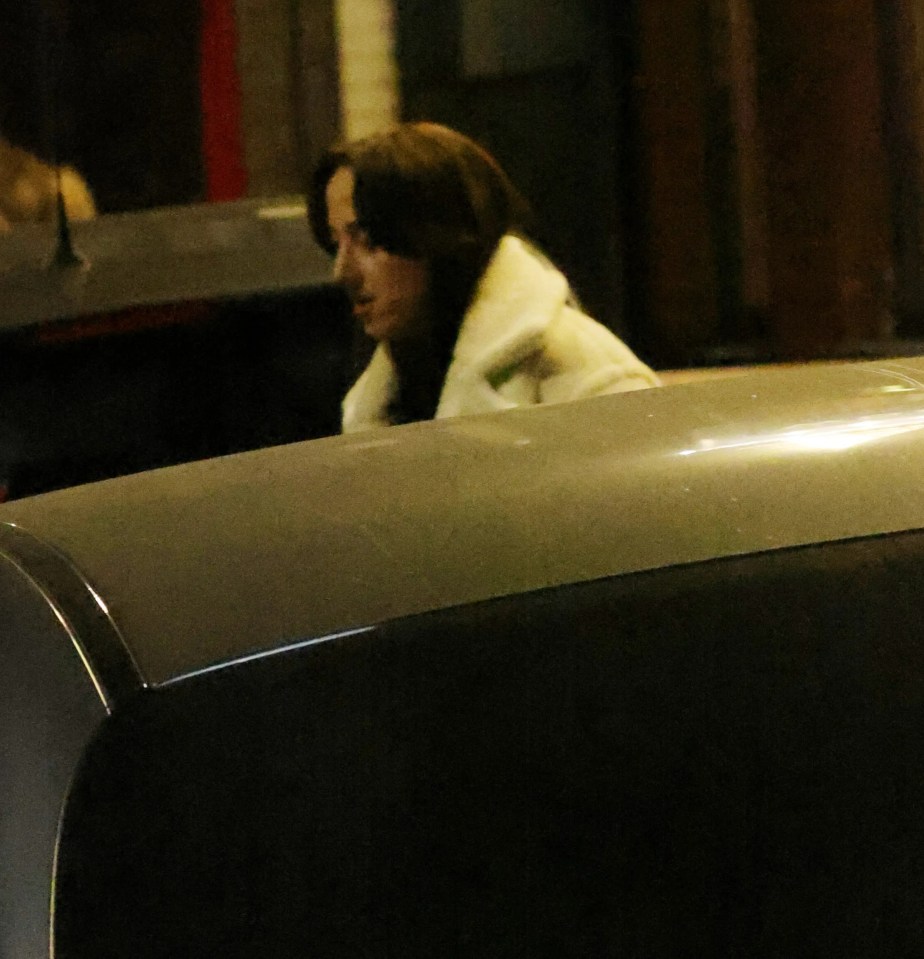 Woman in a white coat leaving a party.