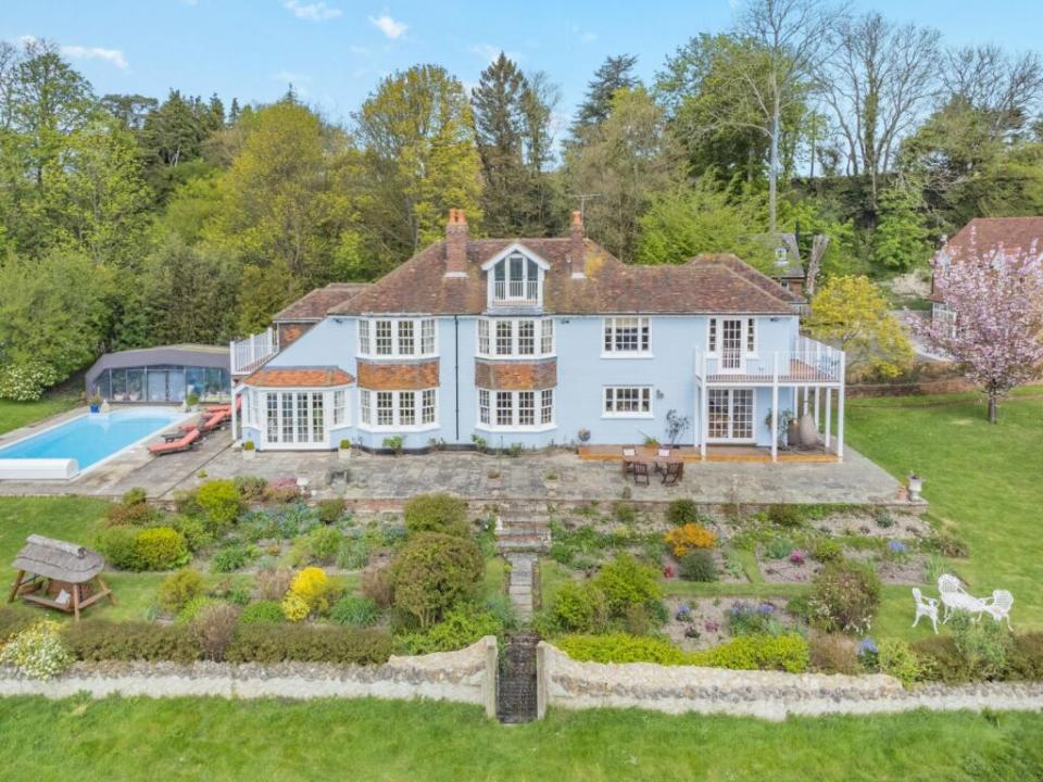 Aerial view of a large blue house with a pool and garden.