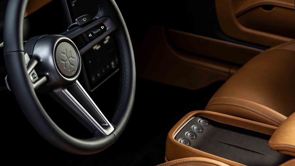 Close-up of a car's interior, showing the steering wheel and tan leather seats.