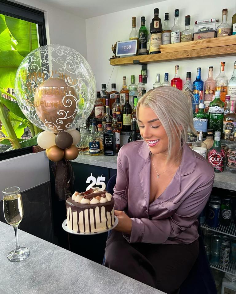 a woman holding a cake with the number 25 on it