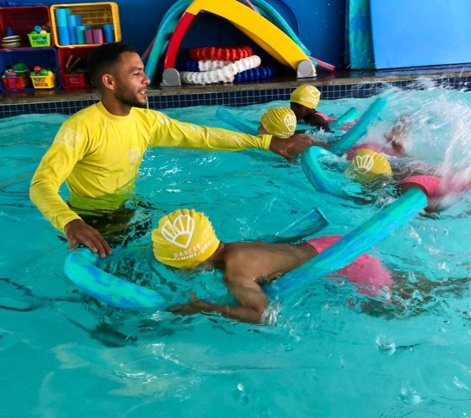 Instructor teaching children to swim using flotation devices.