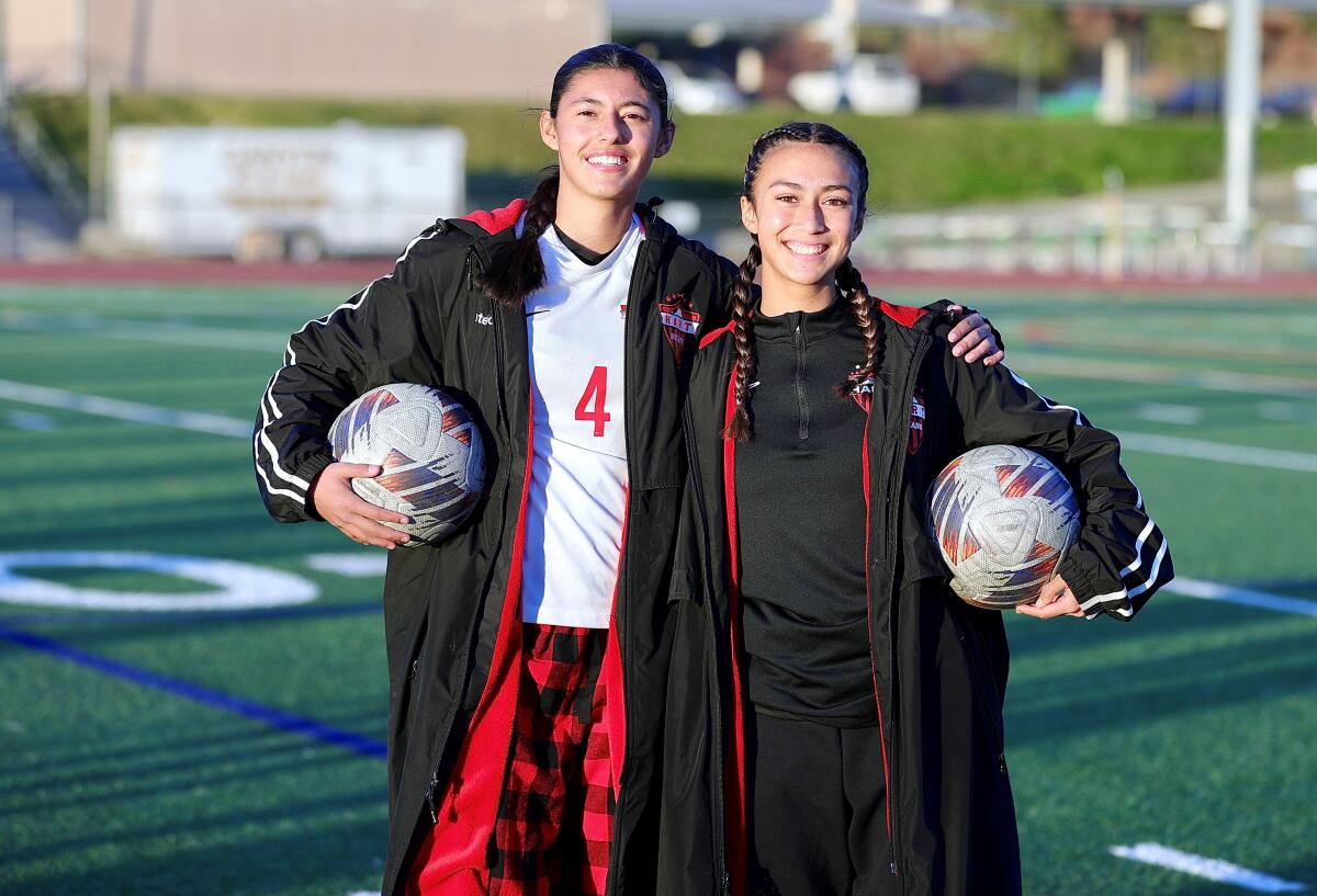 Hart High seniors Gianna Costello (left) and Mia Rodriguez pose for a photo on the soccer field.