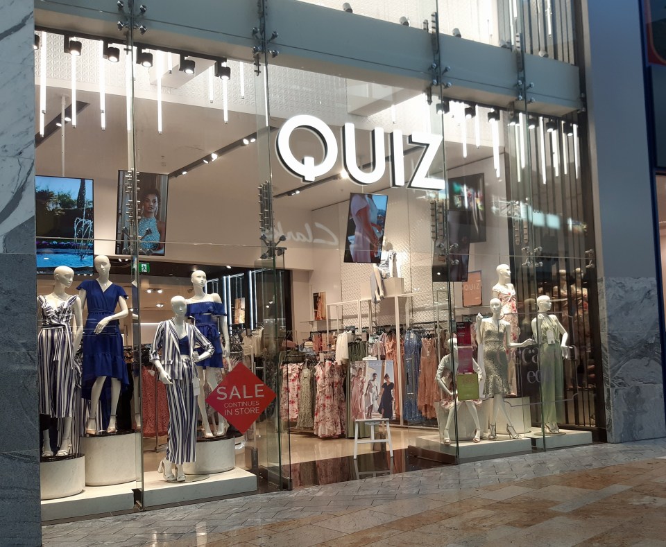 Quiz clothing store storefront with mannequins displaying dresses and suits.