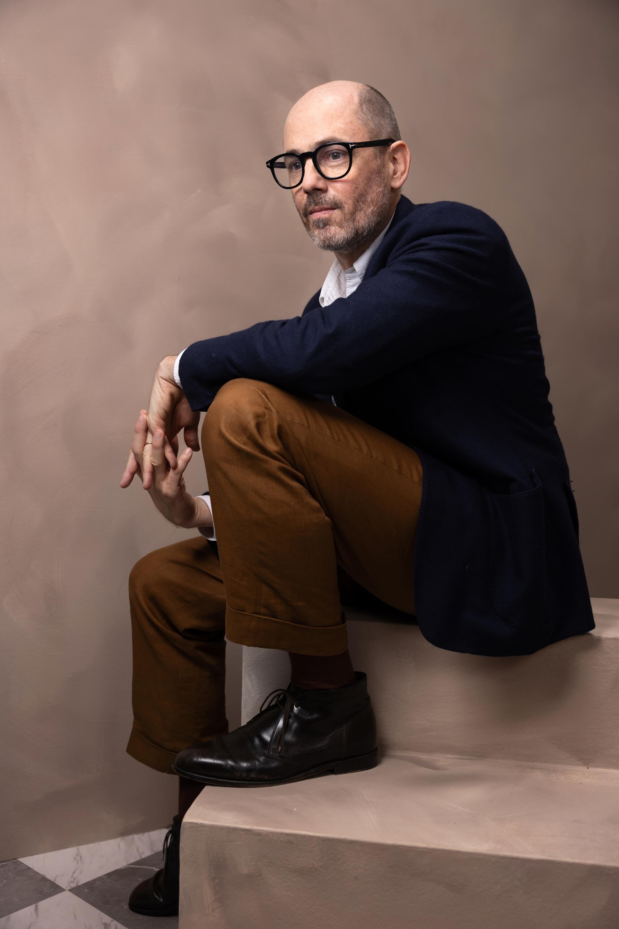 Edward Berger sits on steps with his arm resting on a knee for a portrait.