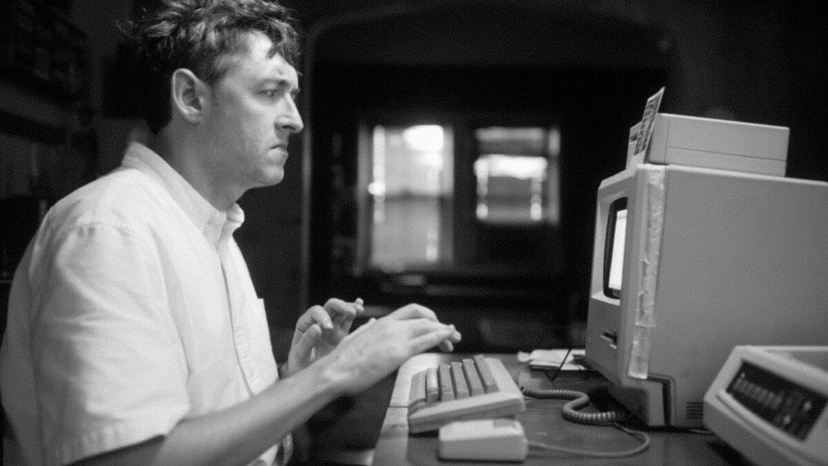 A nervous man types at a computer in the 1980s.