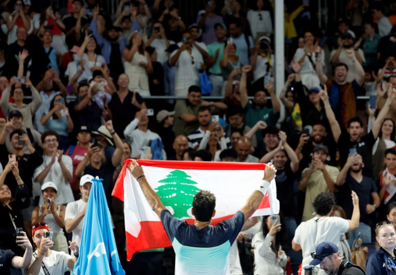 Tennis - Australian Open - Melbourne Park, Melbourne, Australia - January 12, 2025 Lebanon's Hady Habib celebrates with a Lebanese flag after winning his first round match against China's Yunchaokete Bu REUTERS/Francis Mascarenhas TPX IMAGES OF THE DAY