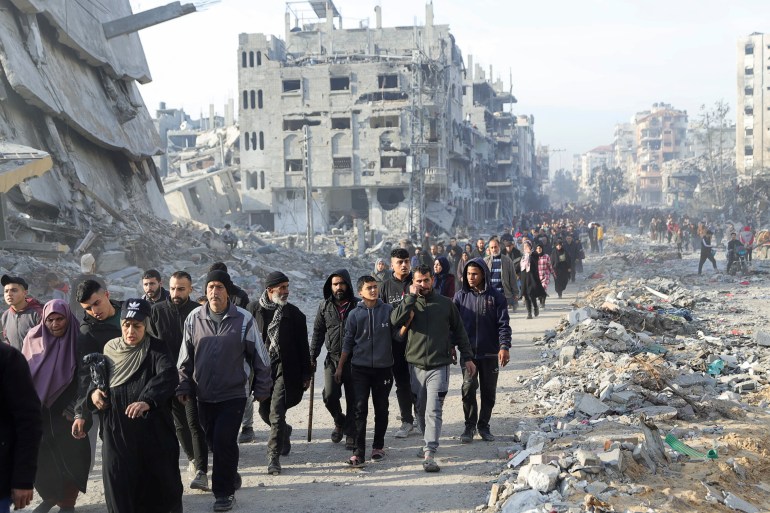 Displaced Palestinians make their way past rubble, as they attempt to return to their homes