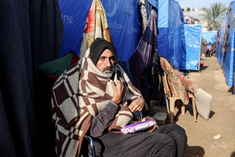 Mohammed al-Mudawwi sits in a wheelchair outside a tent