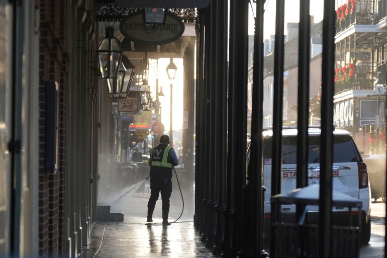 A street cleaner power-washes the sidewalk on Toulouse Street, off Bourbon Street in New Orleans.