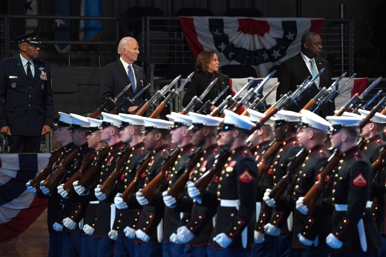 Joe Biden attends a farewell ceremony featuring lines of military members in their dress uniforms, holding rifles.